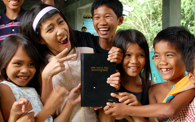A group of kids hold up the Kinaray-a New Testament.